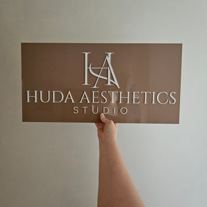 Acrylic Business Logo Sign in taupe brown acrylic with white writing for Huda Aesthetic Studio