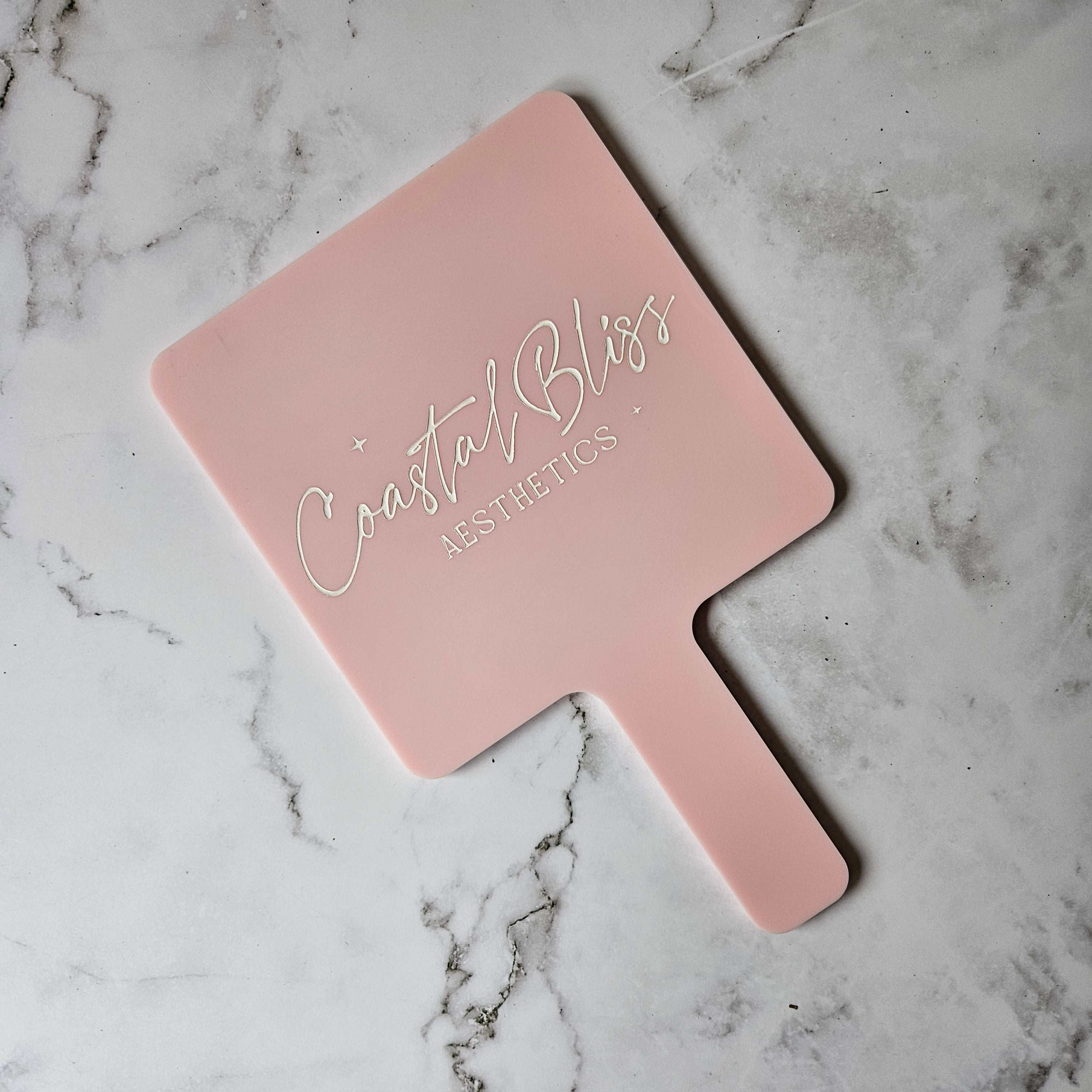 Custom Handheld Mirror with Logo for Aesthetic Injectable Clinic - Square handheld mirror in baby pink acrylic with White Logo