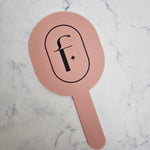 Oval handheld mirror personalised with black logo, in pink clay acrylic